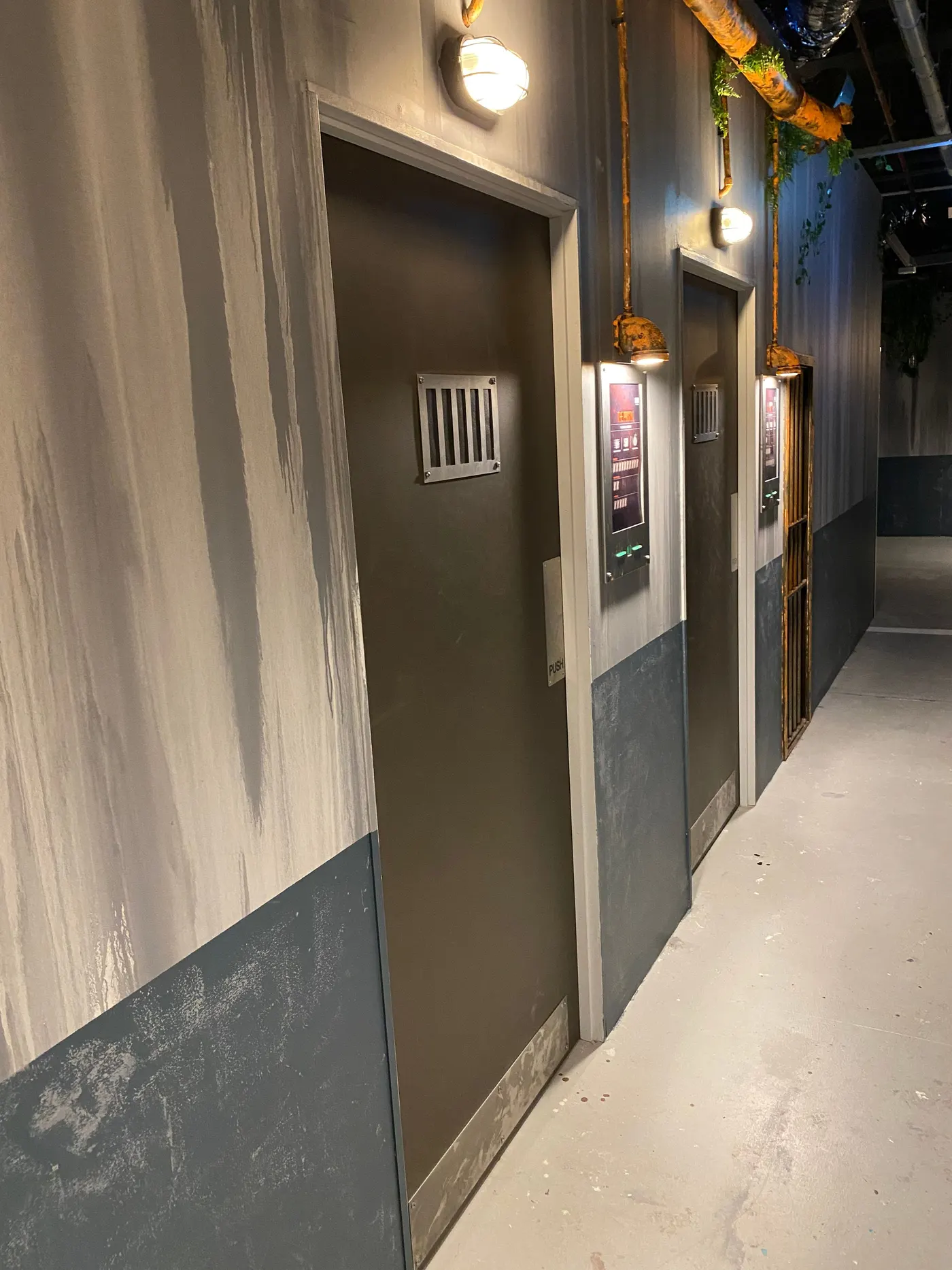 Couloir d’un centre terminé : portes de cellules à grille, écrans de score et appliques murales