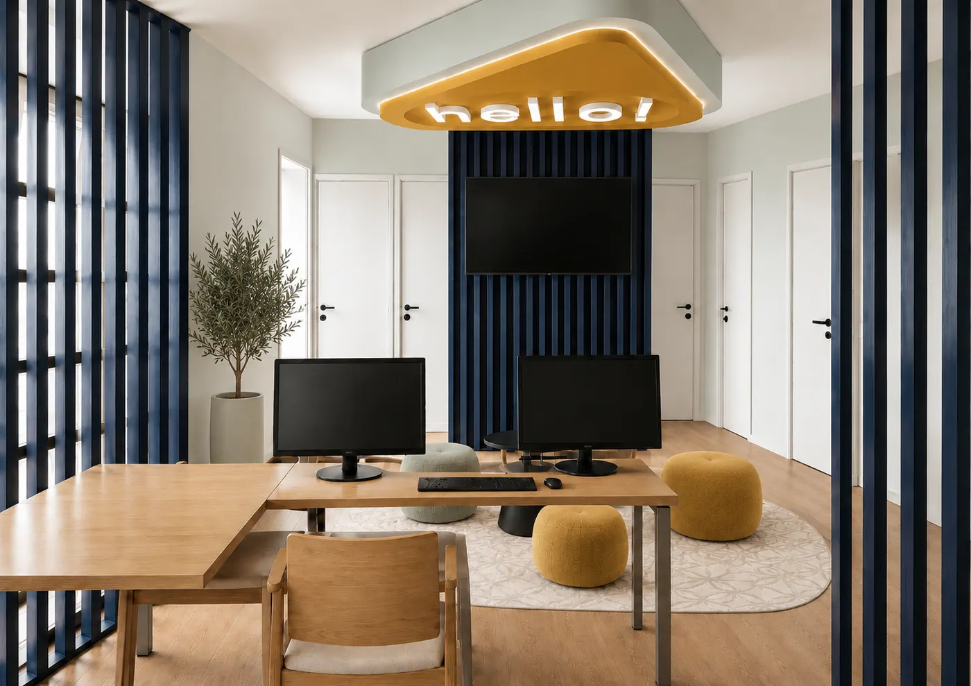 Zone de travail : bureau en bois avec deux écrans, poufs jaunes et plantes, derrière des claustras bleus