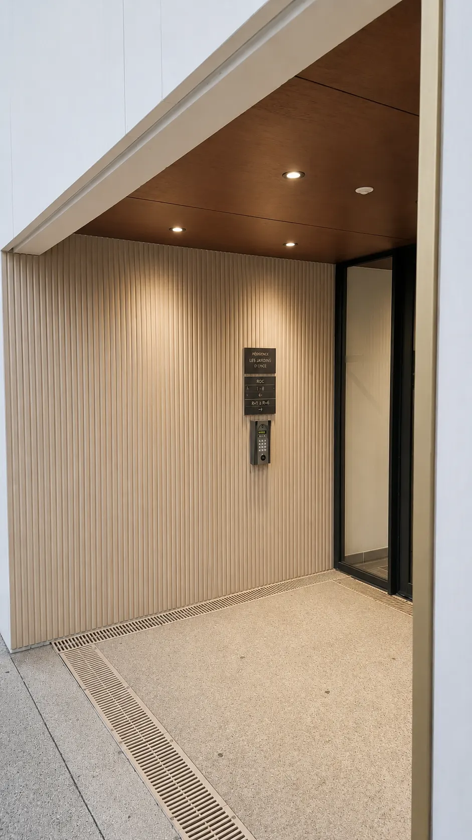 Sas d’entrée : habillage à lames verticales, plafond bois et interphone