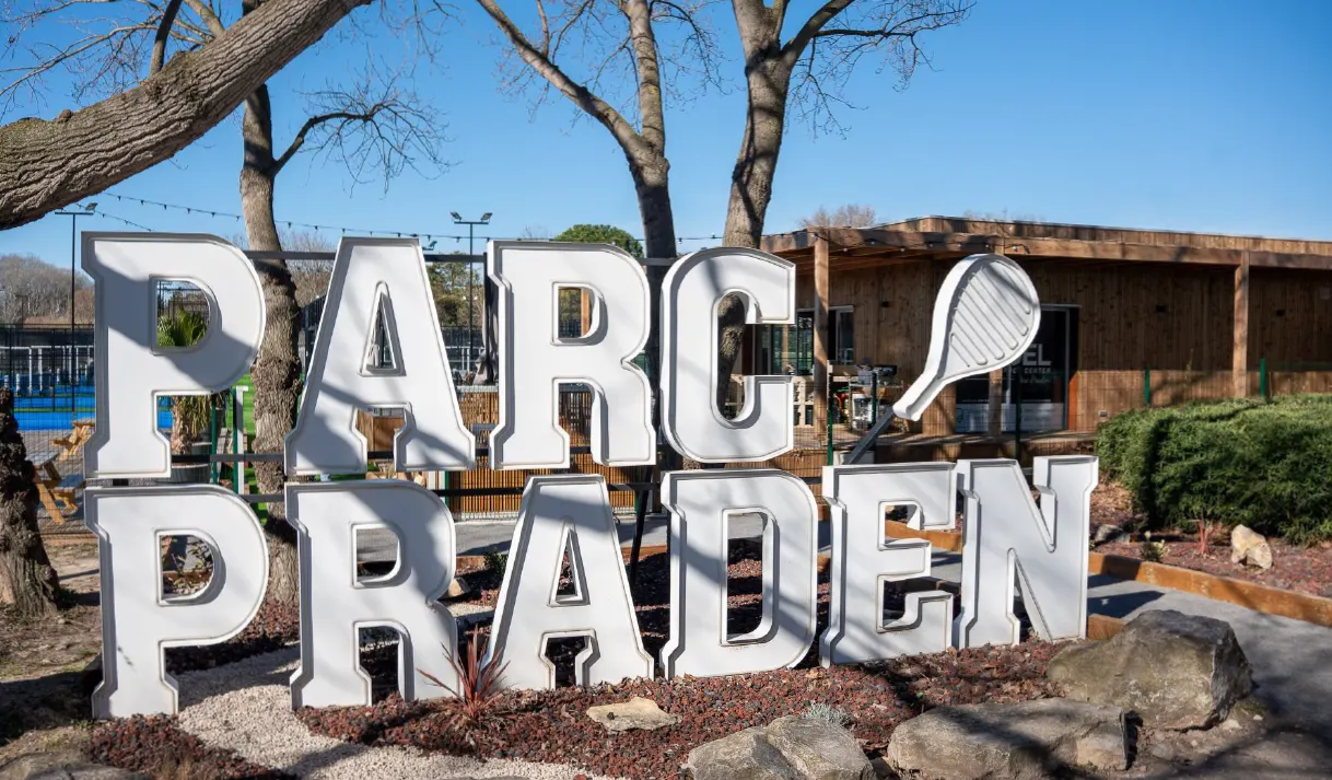L’enseigne réalisée : grandes lettres blanches « PARC PRADEN » et raquette, devant le club-house