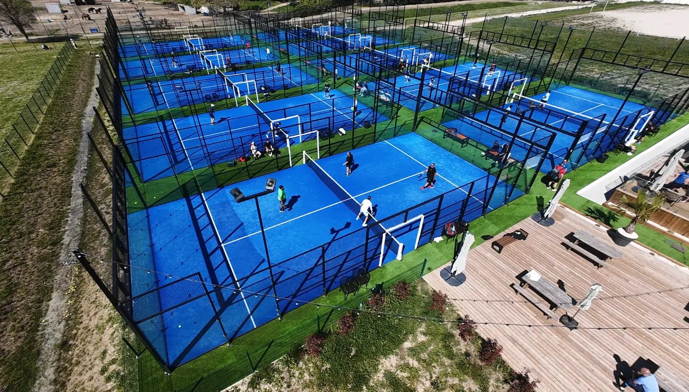 Photographie des terrains de padel actuels, à ciel ouvert, parties en cours, à côté de la terrasse du club-house
